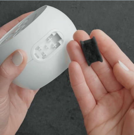 Hands holding a Transcend Micro CPAP device and filter, showing the open filter slot and clearly indicating where the air filter is inserted.
